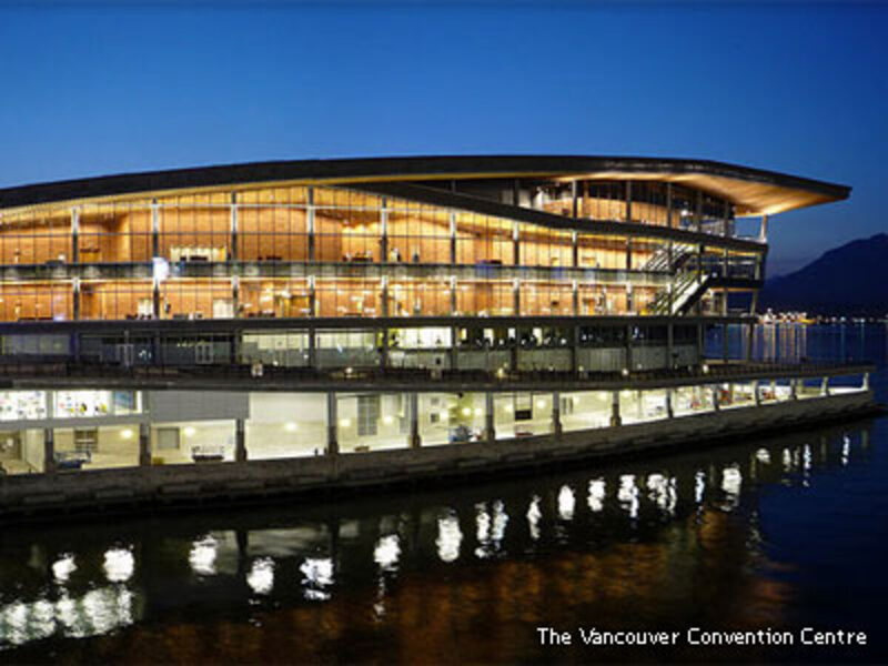 The Vancouver Convention Centre at twilight, lit interior visible through full-height glass facade