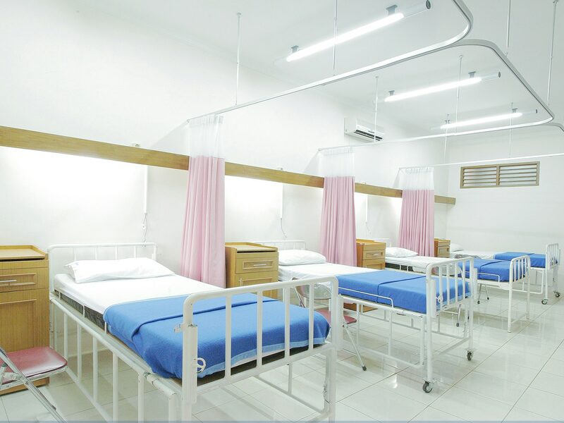 A hospital ward with painted walls, beds, and curtains