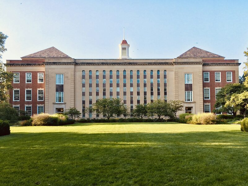 A stone and brick university campus building with a clock tower